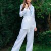 Woman dressed in white linen jacket, blue shirt and white pants