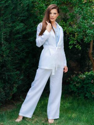 Woman dressed in white linen jacket, blue shirt and white pants