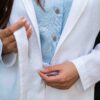 Woman dressed in white linen jacket, blue shirt and white pants