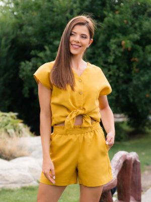 Woman dressed in yellow linen shirt with longs sleeves and coconut buttons and yellow pants