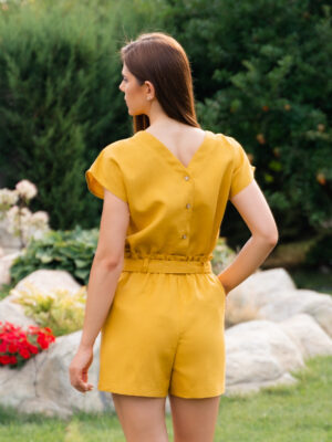 Woman dressed in yellow linen shirt with longs sleeves and coconut buttons and yellow pants