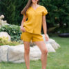 Woman dressed in yellow linen shirt with longs sleeves and coconut buttons and yellow pants