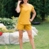 Woman dressed in yellow linen shirt with longs sleeves and coconut buttons and yellow pants