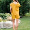 Woman dressed in yellow linen shirt with longs sleeves and coconut buttons and yellow pants