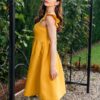 Woman in a garden, dressed in yellow linen dress