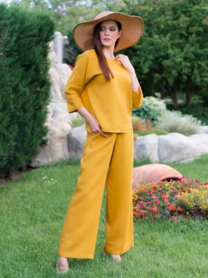 Woman dressed in yellow linen shirt with longs sleeves and coconut buttons and yellow long pants