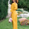 Woman dressed in yellow linen shirt with longs sleeves and coconut buttons and yellow long pants