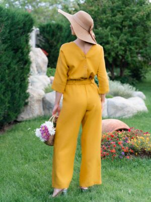 Woman dressed in yellow linen shirt with longs sleeves and coconut buttons and yellow long pants