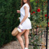 Woman in a garden dressed in white linen shorts and white linen top