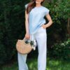 Woman dressed in blue linen shirt with short sleeves and white long pants