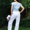 Woman dressed in blue linen shirt with short sleeves and white long pants