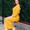 Woman dressed in yellow linen shirt with longs sleeves and coconut buttons and yellow long pants