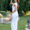 Woman wearing a white t-shirt and white long trousers with a hat on her head is holding a knitted bag