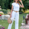 Woman wearing a white t-shirt and white long trousers with a hat on her head is holding a knitted bag