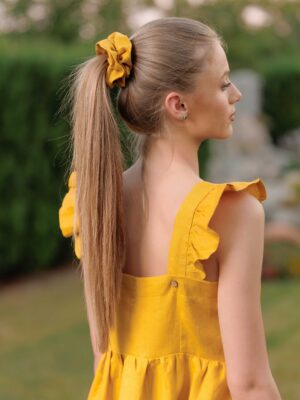 Woman waering yellow linen dres and yellow linen scrunchie on her hair