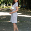 A woman wearing an organic cotton dress with a tie at the waist is walking in the park