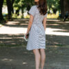 A woman wearing an organic cotton dress with a tie at the waist is walking in the park