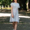 A woman wearing an organic cotton dress with a tie at the waist is walking in the park