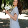 A woman wearing an organic cotton dress with a tie at the waist is walking in the park