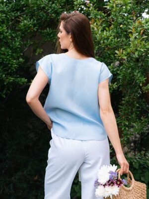 Woman in a garden dressed in white linen shorts and blue linen shirt