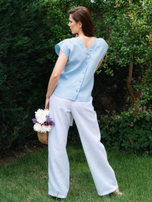 Woman in a garden dressed in white linen shorts and blue linen shirt