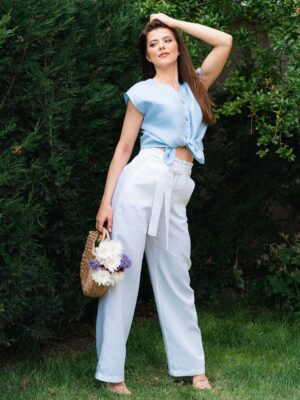 Woman in a garden dressed in white linen shorts and blue linen shirt