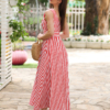Woman with brown hair wearing a long red stripped dress in a flower garden