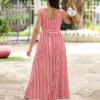 Woman with brown hair wearing a long red stripped dress in a flower garden