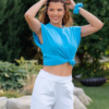A young woman with brown hair wearing organic cotton blue color t-shirt and white long trousers