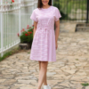 A woman in a pink dress and white sneakers standing outdoors