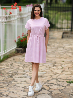 A woman in a pink dress and white sneakers standing outdoors