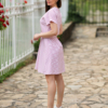 A woman in a pink dress and white sneakers standing outdoors