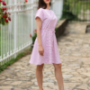 A woman in a pink dress and white sneakers standing outdoors