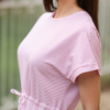 A woman in a pink dress and white sneakers standing outdoors