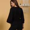 Woman with brown hair wearing black organic cotton wide sleeves blouse and black organic cotton long pants