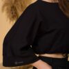 Woman with brown hair wearing black organic cotton wide sleeves blouse and black organic cotton long pants