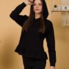 Woman with brown hair wearing black long-sleeved sweatshirt with a hood and ruffles, and black organic cotton long pants