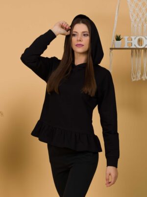 Woman with brown hair wearing black long-sleeved sweatshirt with a hood and ruffles, and black organic cotton long pants