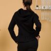 Woman with brown hair wearing black long-sleeved sweatshirt with a hood and ruffles, and black organic cotton long pants