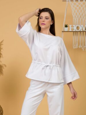 Woman with brown hair wearing white organic cotton wide sleeves blouse and white organic cotton wide long pants
