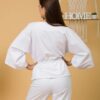 Woman with brown hair wearing white organic cotton wide sleeves blouse and white organic cotton wide long pants