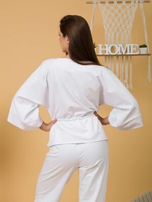 Woman with brown hair wearing white organic cotton wide sleeves blouse and white organic cotton wide long pants