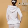 Woman with brown hair wearing white long-sleeved sweatshirt with a hood and ruffles and white organic cotton long pants