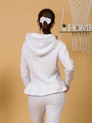 Woman with brown hair wearing white long-sleeved sweatshirt with a hood and ruffles and white organic cotton long pants