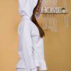 Woman with brown hair wearing white long-sleeved sweatshirt with a hood and ruffles and white organic cotton long pants
