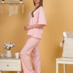 Woman with blond hair wearing pink organic cotton pajama set of short sleeve blouse and long pants
