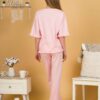 Woman with blond hair wearing pink organic cotton pajama set of short sleeve blouse and long pants