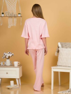 Woman with blond hair wearing pink organic cotton pajama set of short sleeve blouse and long pants