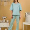 Woman with blond hair wearing turquoise organic cotton pajama set of short sleeve blouse and long pants
