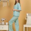 Woman with blond hair wearing turquoise organic cotton pajama set of short sleeve blouse and long pants